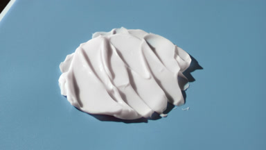 Turntable shot of white day cream smears on blue background