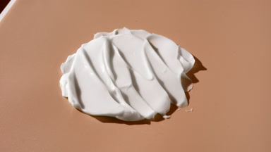 Turntable shot of white day cream smears on beige background