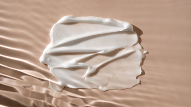 White body cream smears on beige background under rippling water