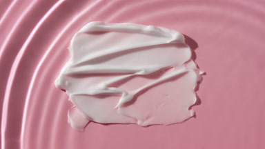 Drop falls down on water on pink background with white cream