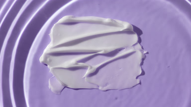 Water drop drips on water on purple background with white cream