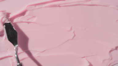 Pink cosmetic cream are being smeared by palette knife