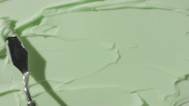 Green cosmetic cream are being smeared by palette knife