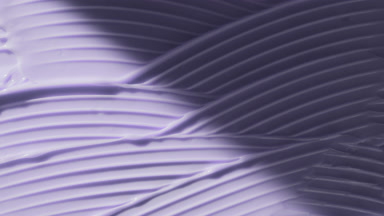 Macro of purple lifting cream wave texture appears from shadow