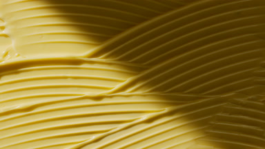 Macro of yellow lifting cream wave texture appears from shadow