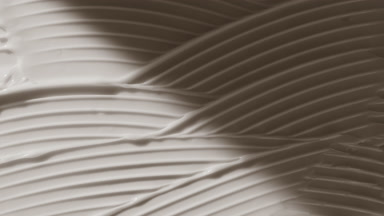 Macro of white lifting cream wave texture appears from shadow