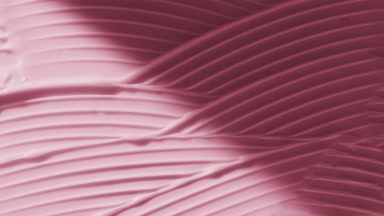 Macro of pink lifting cream wave texture appears from the shadow