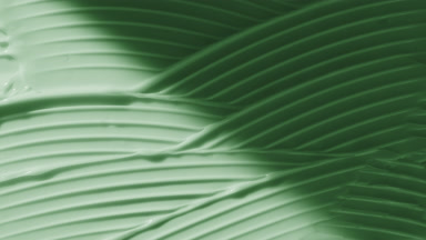 Macro of green lifting cream wave texture appears from the shadow