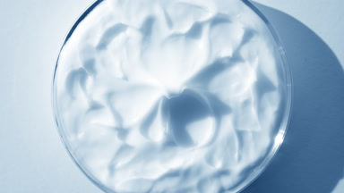 Extreme close-up turntable shot of blue cream on watch glass