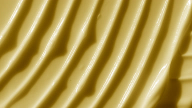 Macro shot of yellow lifting day cream with moving light source