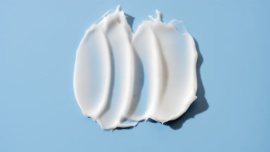 Macro of white lightening cream smears on pale blue background
