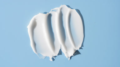 Whitening cream smears on blue background with changing lighting