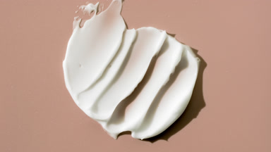 White cream smears on beige background with changing lighting