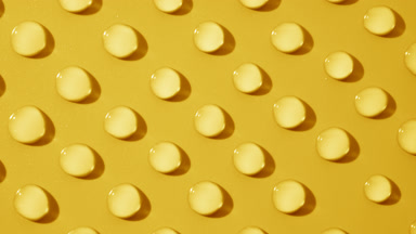 Top view macro of moving transparent drops on yellow background