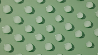 Top view macro of moving transparent drops on green background