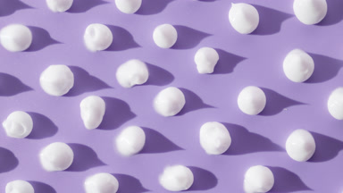 White cream drops on violet background with moving lighting
