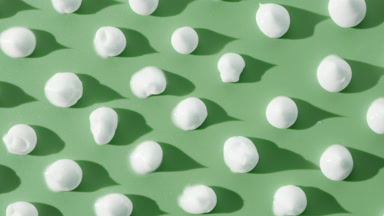 White cream drops on green background with moving lighting