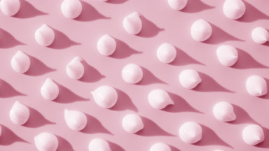 Pink cream drops on pale pink background with moving lighting