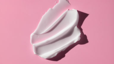 Lightening cream smears on pink background with moving lighting