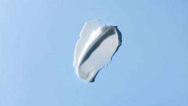 Two white face cream smears on blue background with moving light