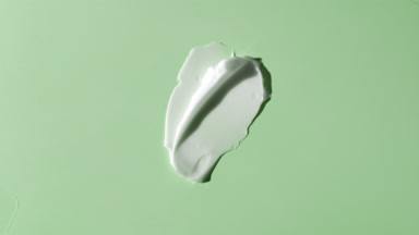 White face cream smears on green background with moving light