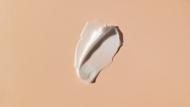 White face cream smears on beige background with moving light