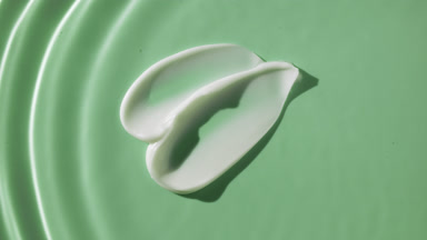 Drop drips on water on green background with two cream smears