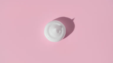 White cream drop appears from shadow turning on pink background