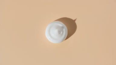 White cream drop appears from shadow turning on beige background