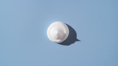 White cream drop turns covering by shadow on blue background