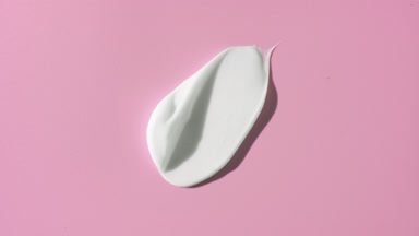 Whitening cream smear on pale pink background with moving light