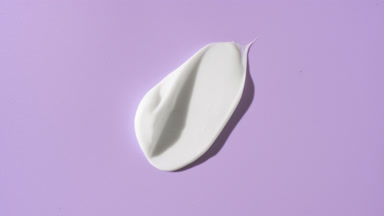 Whitening cream smear on purple background with moving light