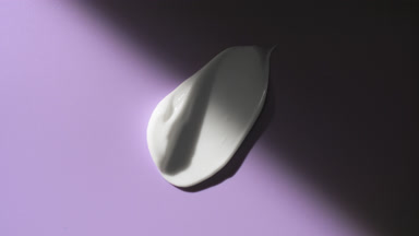 Lightening cream smear appears from shadow on purple background