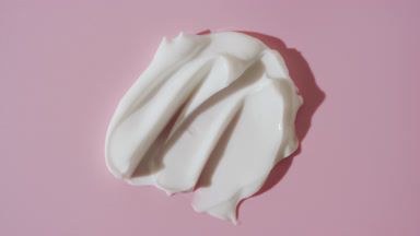 White cream smears are covered by shadow on pink background