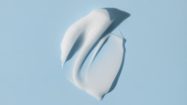 Face cream smears appear from shadow on pale blue background