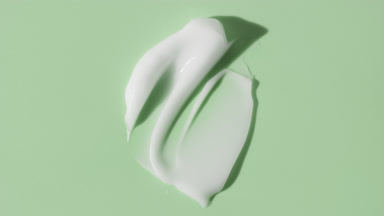 Face cream smears appear from the shadow on green background