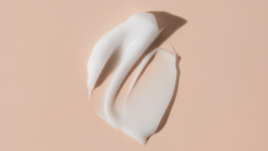 Face cream smears appear from the shadow on beige background