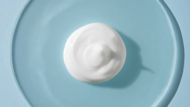 Cream drop on watch glass appears from shadow on blue background