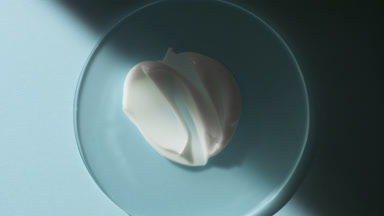 Body cream smears on glass appear from shadow on blue background