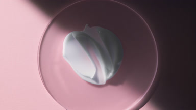 Body cream smears on glass appear from shadow on pink background