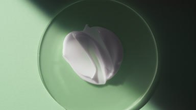 Cream smears on glass appear from shadow on green background