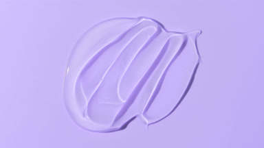 Macro of face gel smears appear from shadow on violet background