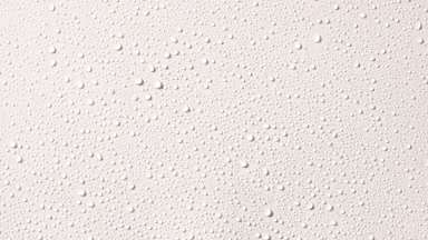 Macro of water drops appear from the shadow on white background