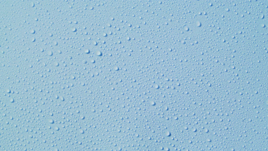 Macro of water drops appear from the shadow on blue background