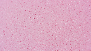 Macro of water drops appear from the shadow on pink background