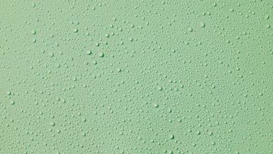 Macro of water drops appear from the shadow on green background
