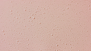 Macro of water drops appear from the shadow on beige background