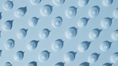 Drops of blue cream appear from the shadow on blue background