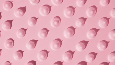Drops of pink cream appear from the shadow on pink background