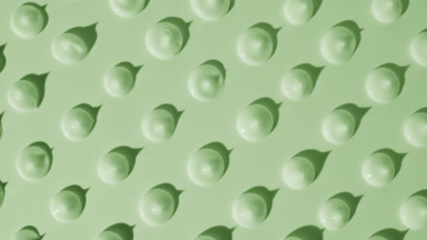 Drops of green cream appear from the shadow on green background
